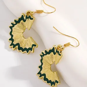 Macro detail of creative pencil shaving drop earrings with gold finish and green enamel