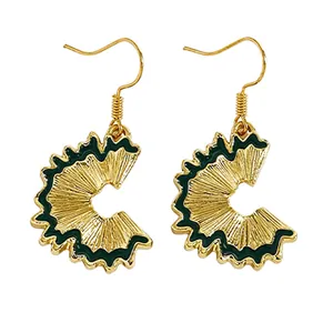 Close-up of creative gold-tone earrings featuring detailed green enamel pencil shaving design