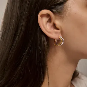 Vue rapprochée de boucles d'oreilles vagues bicolores irrégulières sur l'oreille du modèle