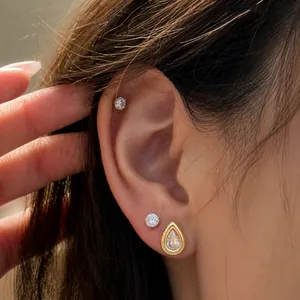 Makroansicht eleganter goldener Tropfen-Zirkon-Ohrringe mit chirurgischer Stahltextur