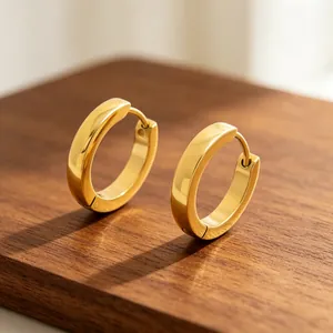 Close-up of elegant gold-plated stainless steel hoop earrings on a rustic wooden base