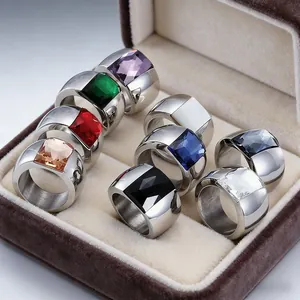 Detailed view of titanium steel wide rings with vibrant multi-colored glass stones in box