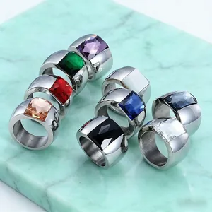 Detailed view of titanium steel wide rings featuring vibrant square-cut glass stones on marble.