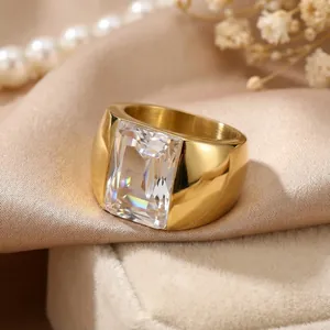 Close-up of gold titanium steel wide band ring with a large rectangular clear emerald-cut stone