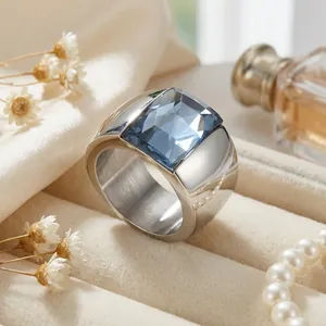 Close-up shot of a wide titanium steel ring featuring a faceted square blue crystal stone