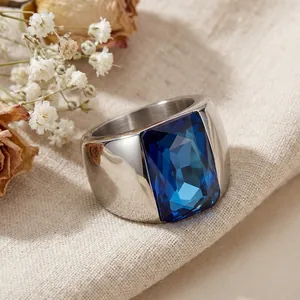 Detailed macro shot of a titanium steel wide band ring with a large blue faceted glass stone