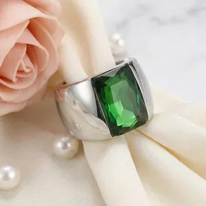Macro detail of wide titanium steel ring featuring a large emerald green faceted glass stone