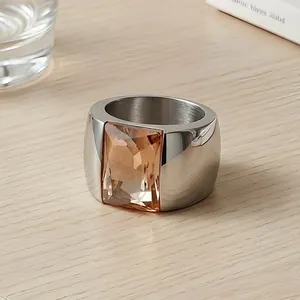 Close-up detail view of a wide stainless steel ring with a large amber glass gemstone