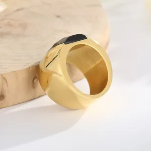 High-angle close-up of a wide gold titanium steel ring featuring a sleek black glass inlay.