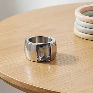 Close-up of a wide titanium steel ring with a rectangular smoky grey glass gemstone.