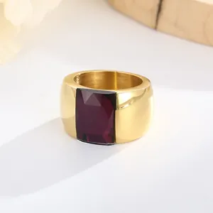 Close-up of wide gold titanium steel ring with faceted purple glass gemstone