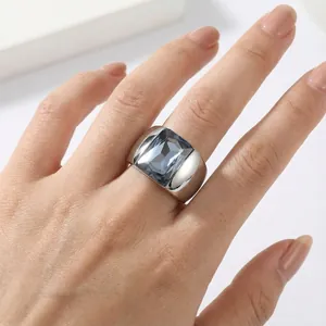 Close-up view of a stainless steel wide band ring with a rectangular blue gemstone