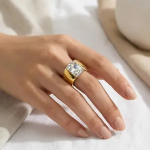 Close-up detail of a wide gold titanium steel ring with a large rectangular clear stone.