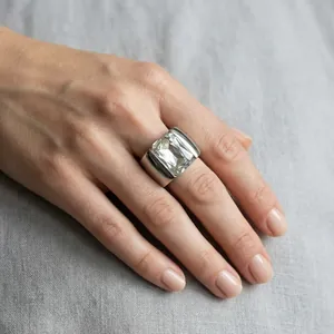 Close-up of a wide titanium steel ring with a large clear rectangular glass stone on hand