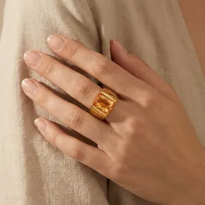 Close-up detail of a modern wide titanium steel ring featuring a large amber glass stone