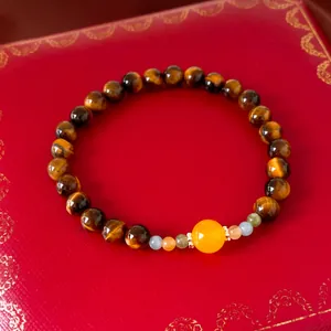 Luxury tiger eye beaded bracelet featuring a central yellow stone on a classic red jewelry box