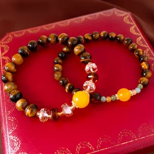 Close-up of Tiger's Eye beaded bracelet with yellow gemstone on a red jewelry box.