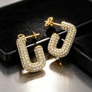 Detailed macro shot of luxury crystal-encrusted geometric U-shaped gold earrings