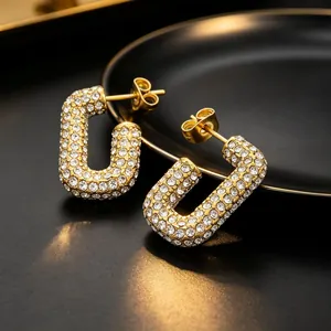 Close-up of gold-plated U-shaped earrings fully encrusted with sparkling white rhinestones