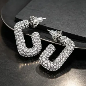 Detailed close-up of silver oval hoop earrings fully encrusted with sparkling rhinestones.