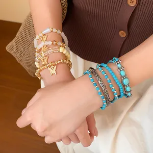 Détail de parures de bracelets bohèmes avec perles turquoise et breloques papillon au poignet
