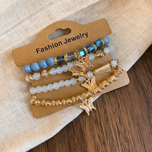 Détail d'un ensemble de quatre bracelets bohèmes avec pendentifs papillons dorés et perles