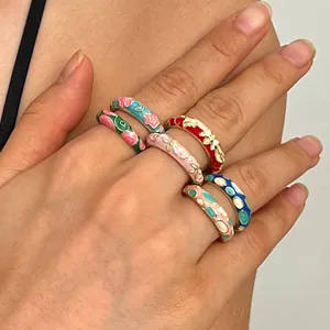 Close-up detail of colorful enamel cloisonné rings featuring intricate floral patterns on hand