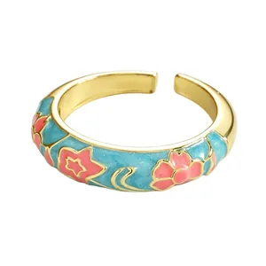 Close-up of gold-toned cloisonné ring with pink floral patterns and light blue enamel coating.