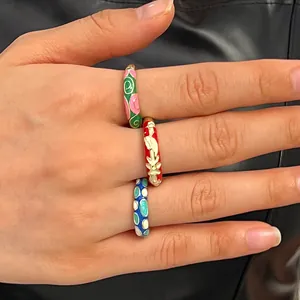 Detailed close-up view of vibrant colorful enamel cloisonné floral rings on a hand