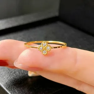 Close-up of gold-plated clover ring with four sparkling inlaid stones on a finger