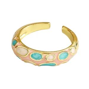 Close-up of a colorful enamel dripping oil ring with gold finish and glitter inlay.