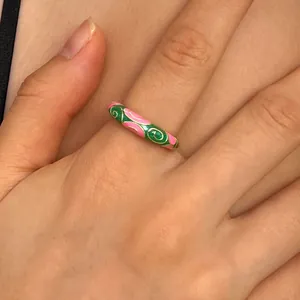 Close-up of a vintage cloisonné enamel ring with colorful floral patterns worn on a finger