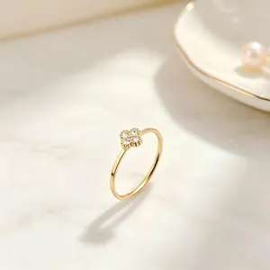 Detail view of a gold clover ring with sparkling diamond-set petals on marble background