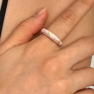 Elegant pink enamel flower ring with gold floral pattern shown on finger for women