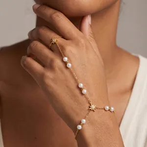 Exquisiter Handschmuck aus Gold mit Sternen und Perlen an einer eleganten Frauenhand