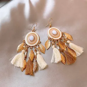 Λεπτομέρεια από boho σκουλαρίκια ρητίνης με χρυσά φύλλα και μαλακές υφασμάτινες φούντες