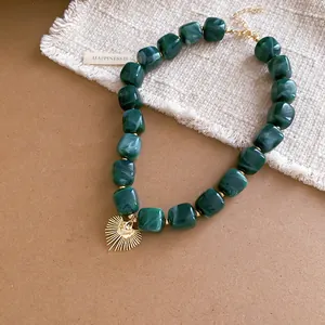 Emerald green marbled resin beaded necklace with gold sunburst heart pendant detail