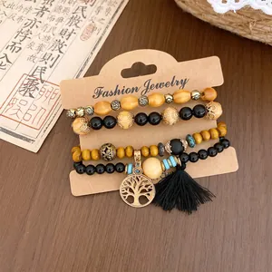 Detailansicht eines 4er-Sets Bohemian-Armbänder mit Holzperlen und Lebensbaum-Anhänger.