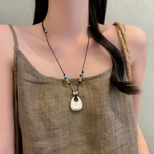 Dettaglio di una collana con ciondolo in argento geometrico con un top in lino