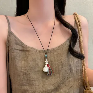 Vista dettagliata di una collana lunga minimalista con nappa colorata su modella