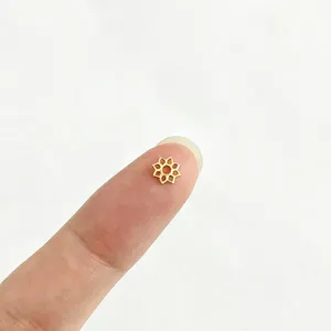 Gros plan d'une petite calotte de perle fleur plaquée or 18 carats sur le doigt