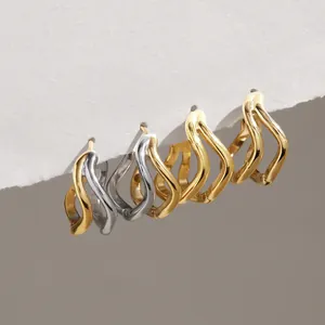 Détail de boucles d'oreilles créoles ondulées double couche en acier inoxydable doré et argent.