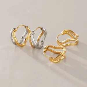 Gros plan de boucles d'oreilles créoles ondulées double couche en acier inoxydable doré et argent