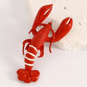 Close-up of vibrant red lobster brooch with white stripes on textured rock background