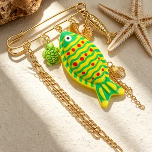 Detailed view of a nautical-style fish and turtle charm brooch with gold chains.