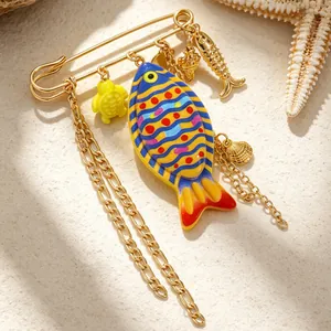 Detailed macro view of colorful fish and shell charms on golden alloy beach brooch.