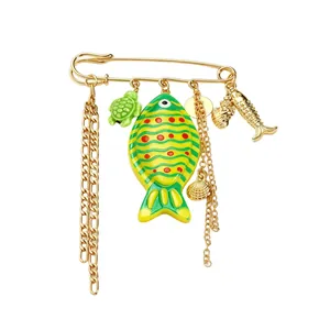 Detailed close-up of a vibrant ocean-themed brooch featuring green fish, turtle, and gold charms.