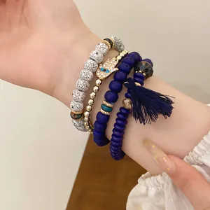 Detail view of ethnic multi-layer beaded bracelet set with Hamsa charm and blue tassel.