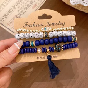 Close-up of four-piece ethnic stretch bracelet set with hamsa charm and tassel