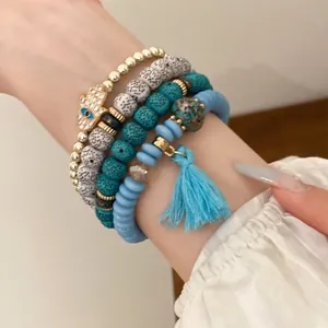 Close-up of bohemian beaded bracelet set featuring a Hamsa hand charm and blue tassel.
